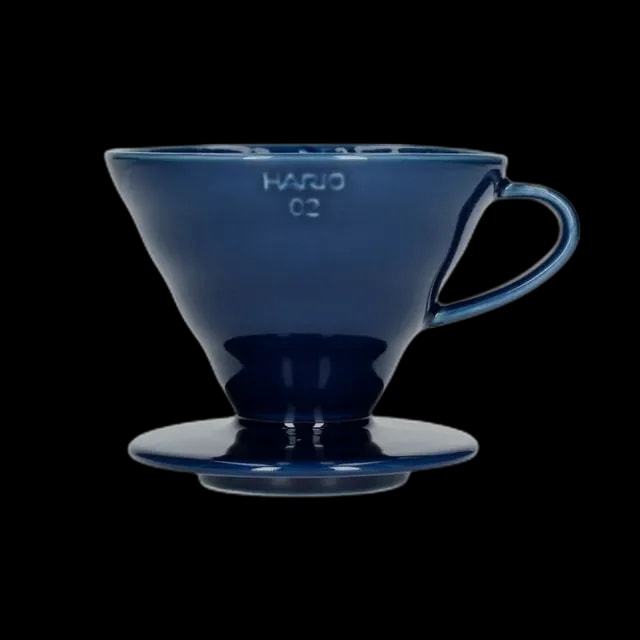 Elegancki ceramiczny dripper Hario V60-02 w głębokim kolorze indygo, idealny do precyzyjnego parzenia kawy metodą pour-over. Kultowy stożkowy kształt z wewnętrznymi żłobieniami zapewnia równomierną ekstrakcję, podkreślając pełnię smaku i aromatu ziaren.