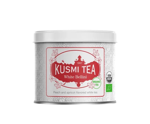 Metalowa puszka herbaty Kusmi Tea White Bellini o pojemności 90g. Na białym tle znajduje się czerwone logo marki oraz informacja o smaku: biała herbata o aromacie brzoskwini i moreli. Puszka oznaczona certyfikatami USDA Organic i EU Organic.
