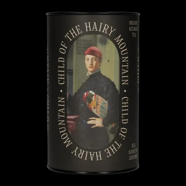 Cylindryczna puszka herbaty czarnej Leaf Liturgy o nazwie „Child of the Hairy Mountain” (Keemun). Opakowanie ozdobione stylizowaną grafiką postaci trzymającej deskorolkę, inspirowaną klasycznym malarstwem z nowoczesnym twistem. Etykieta utrzymana w czarnej kolorystyce z białym napisem, podkreślająca charakter kolekcji. Waga: 60 g, herbata organiczna.