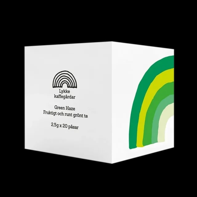 Opakowanie herbaty Lykke Kaffegårdar Green Haze, zawierające 20 saszetek. Białe pudełko z minimalistycznym designem ozdobione zieloną tęczą w różnych odcieniach, od ciemnej zieleni po pastelowy odcień. Napis 'Green Haze Fruktigt och runt grönt te' podkreśla owocowy i pełny smak zielonej herbaty. Elegancka prezentacja herbaty premium.