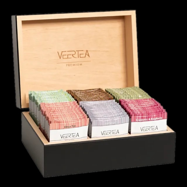 Skrzynka prezentowa VEERTEA Premium z drewna, wypełniona różnokolorowymi paczkami herbat, w tym smaki jak Citrus Tea, Earl Grey, oraz Cranberry & Raspberry, prezentowana na czarnym tle