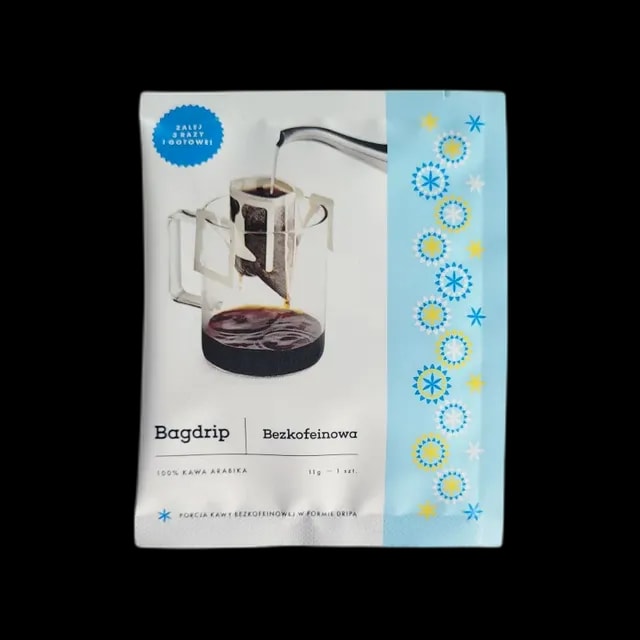 Opakowanie bezkofeinowej kawy Bagdrip z 100% arabiki zawiera pojedynczą saszetkę drip coffee do zaparzania bez użycia sprzętu. Na froncie znajduje się wizualizacja zaparzania kawy w kubku z filtrem zawieszanym, z hasłem „Zalej, zgraj i gotowe!” oraz niebieskimi akcentami graficznymi.