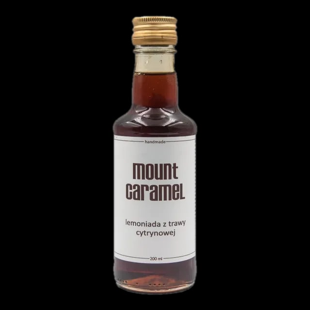 Mała przezroczysta butelka z ciemną lemoniadą 'Trawa Cytrynowa' Mount Carmel, ręcznie robiona, o pojemności 200 ml, z białą etykietą informującą o smaku i marce