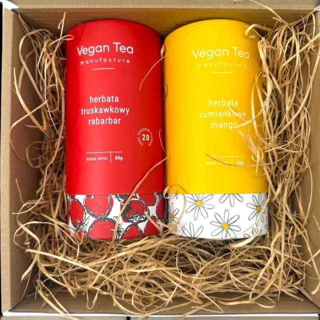 Zestaw dwóch herbat Vegan Tea w ozdobnych tubach – truskawkowy rabarbar (80 g) i rumiankowe mango (55 g) – zapakowany w pudełko z naturalną wyściółką.